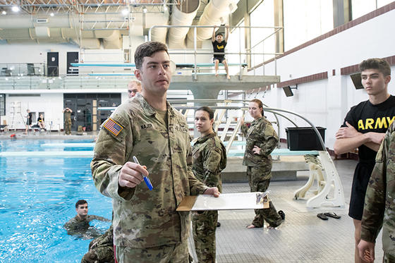 Students and Instructors gather around and in a swimming pool for ROTC water survival training